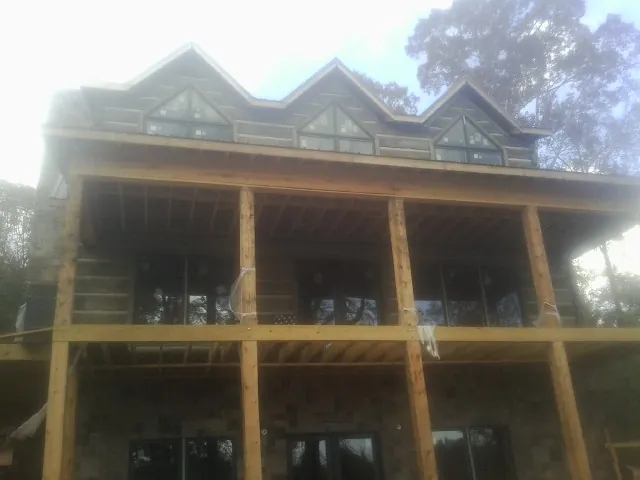 Dormers and porch framing on a large log home under construction — Roof Coating work by our crew in Winthrop