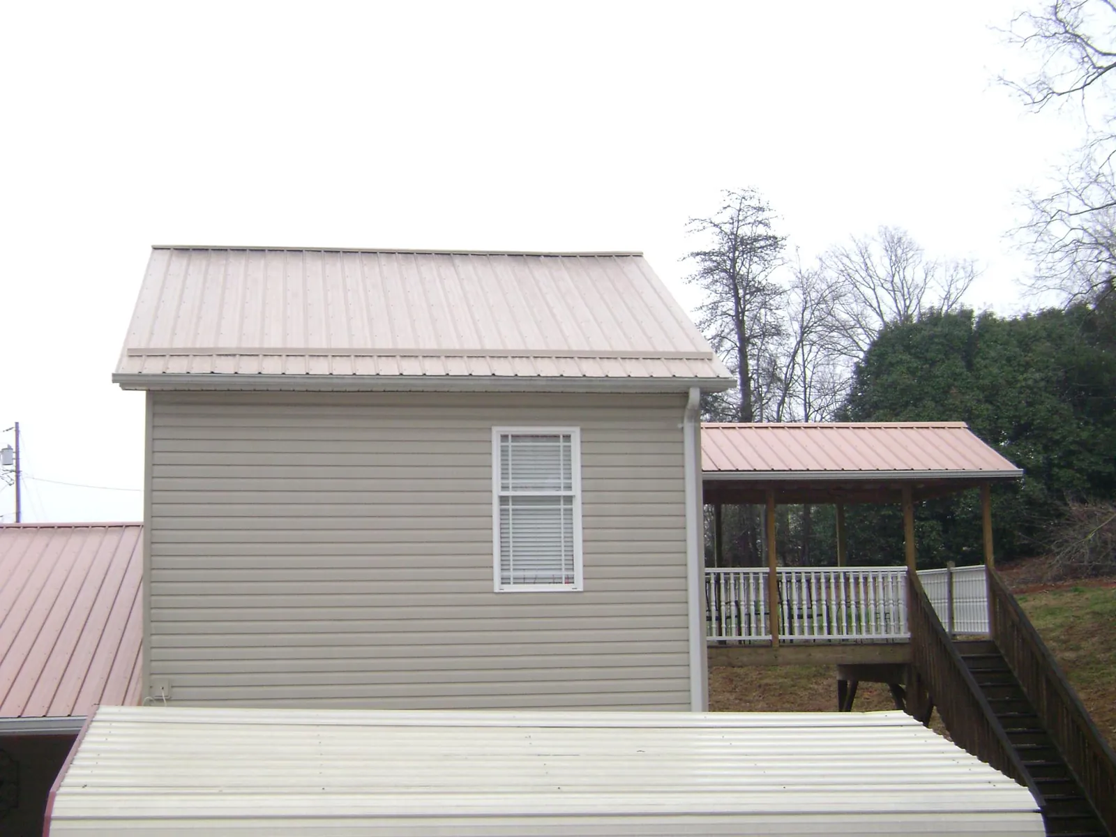 Tan metal roofs on a two story addition and attached porch, from a Roof Replacement job in Winthrop