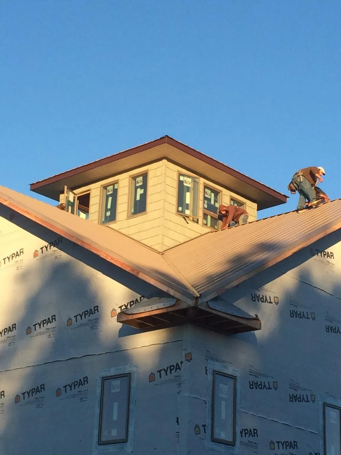 Roofers working around a rooftop cupola on a new metal roof at sunset — Roof Waterproofing in Winthrop by Roofing Brothers